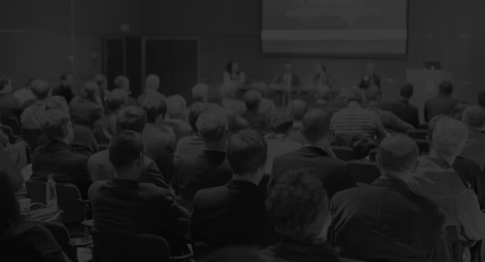 Deep-Dive into Decarbonization Audience attending a conference with a panel of speakers on stage.
